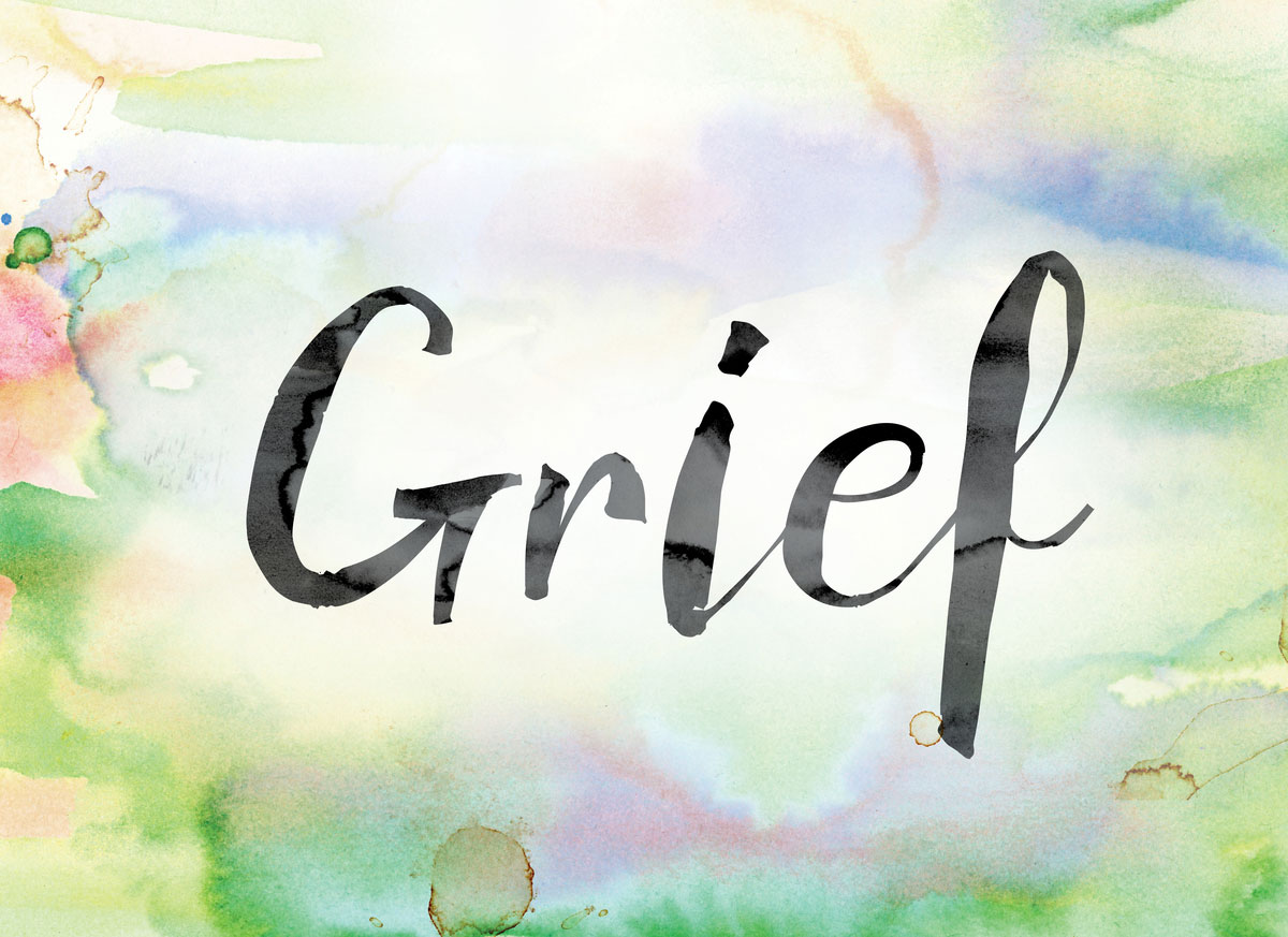 The word "Grief" painted in black ink over a colorful watercolor washed background concept and theme.